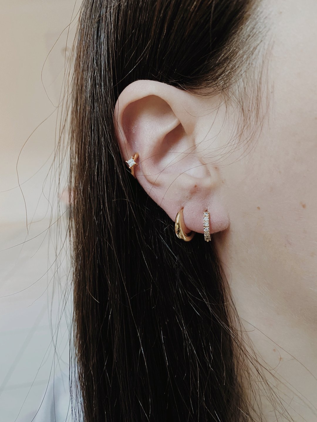 princess cut cz stone in 14k gold vermeil huggy hoops layered on earlobe with domed hoops and white stone huggies