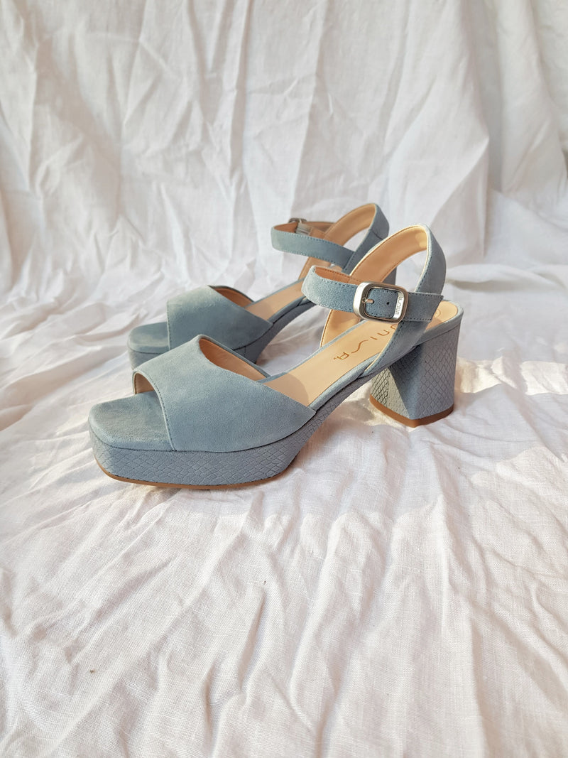 blue suede platform heels with ankle strap and silver buckle pair on white background